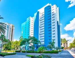 A high rise blue and white building with well maintenanced landscaping 